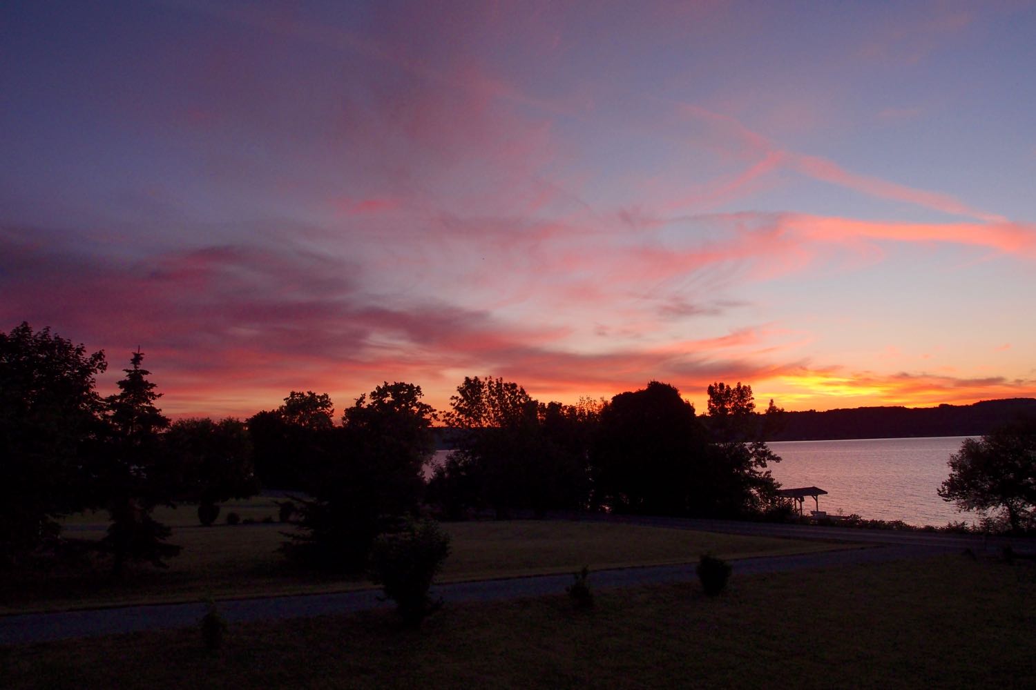 Red clouds over trees and a bit of Cayuga Lake about an hour before sunrise.