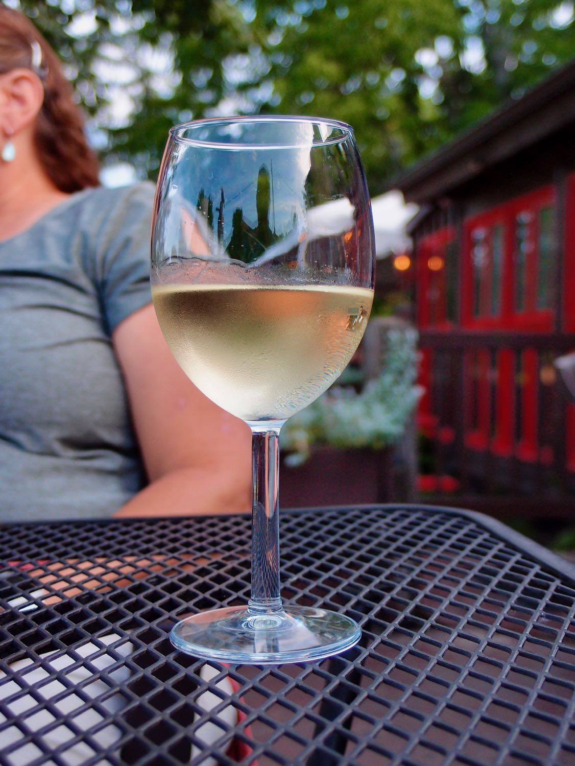 Photo of a wineglass with condensation outtide on an metal tabletop.