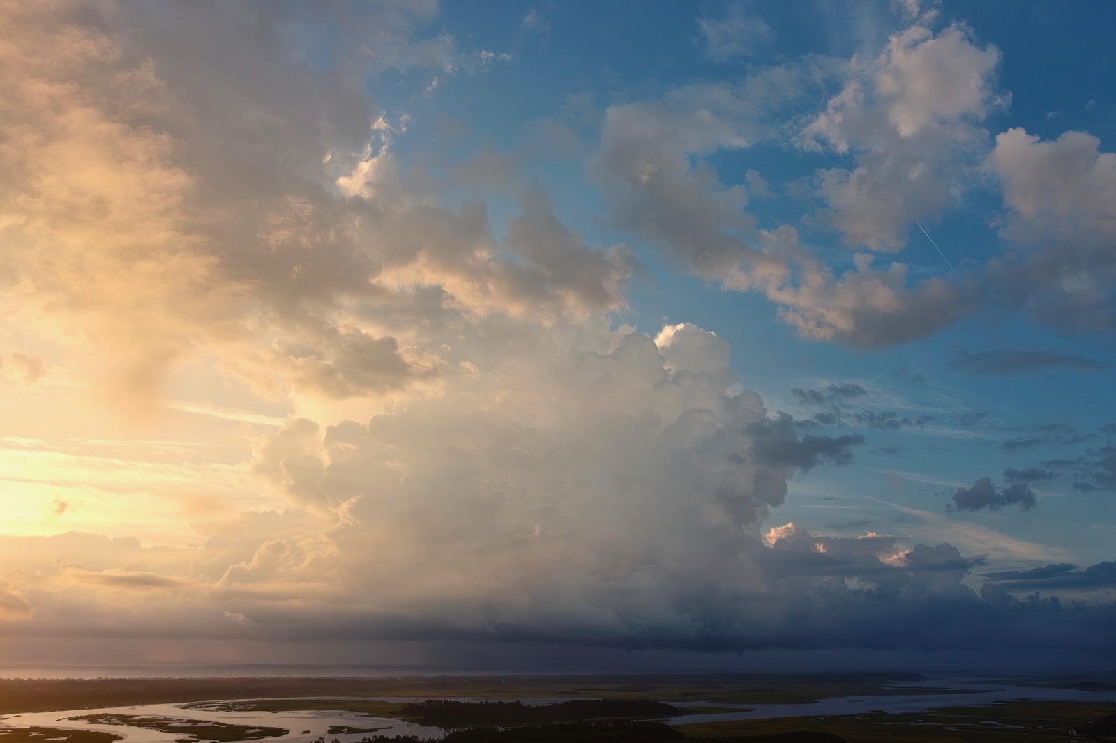 Drone shot of cumulous clouds above wetlands illuminated by a low morning sun