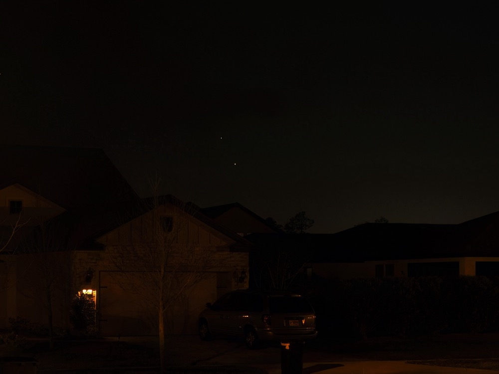 Venus and Jupiter approaching near-conjunction as viewed from my front porch, low on the horizon above a house across the street.