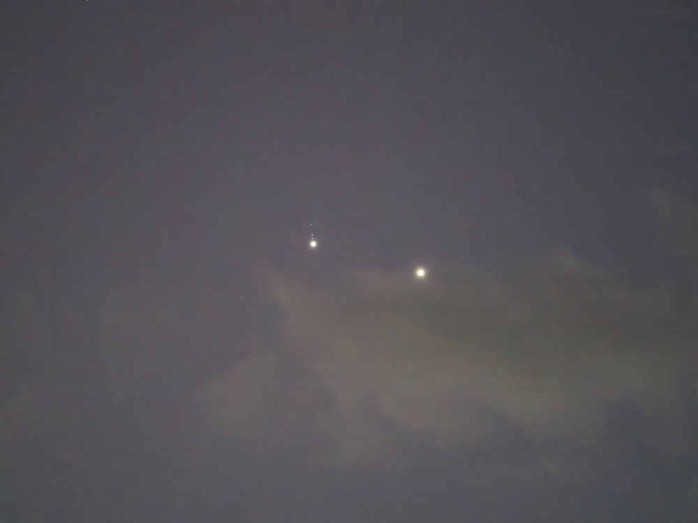 Telephoto image of Jupiter and Venus near conjuntion not long after sunset with some clouds visible along with 3 Jovian moons