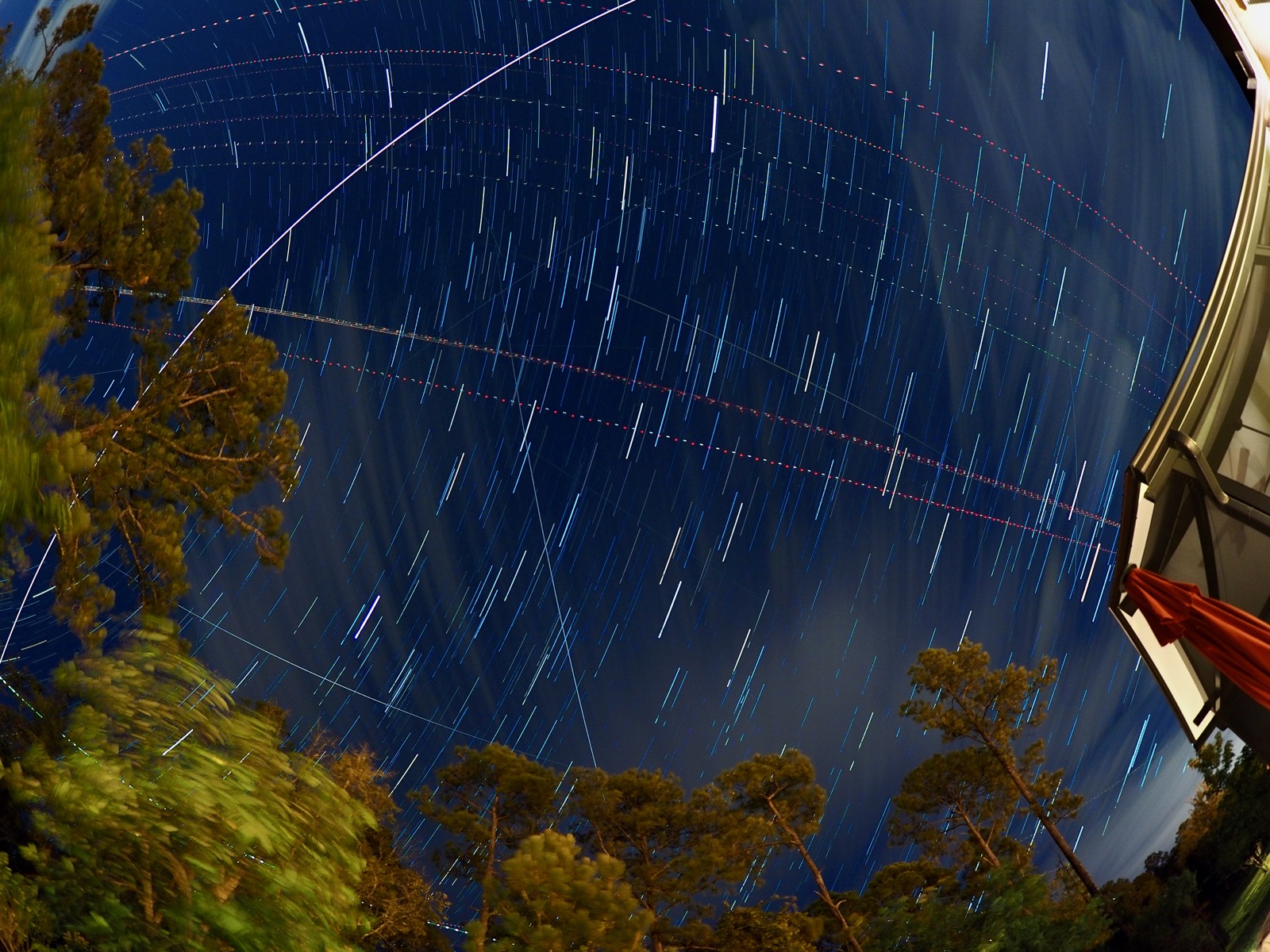 Overhead view of the night sky in live composite mode showing the light trails of the International Space Station, several satellites and aircraft