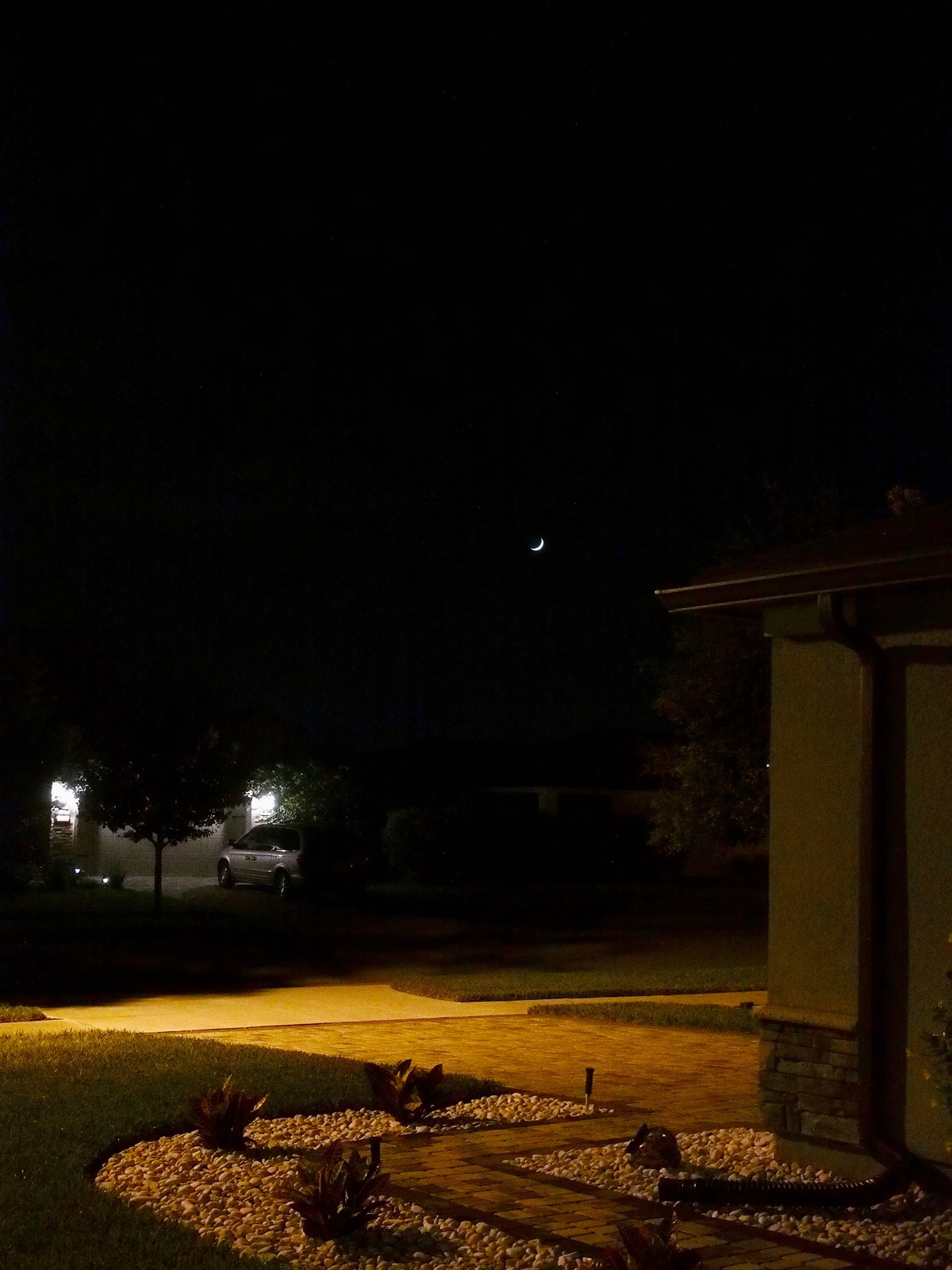 Crescent moon low over a dark suburban landscape
