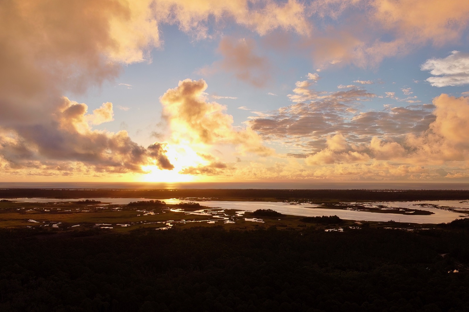 Drone shot looking east toward the sun rising over the Atlantic Ocean with the Tolomato River in the foreground
