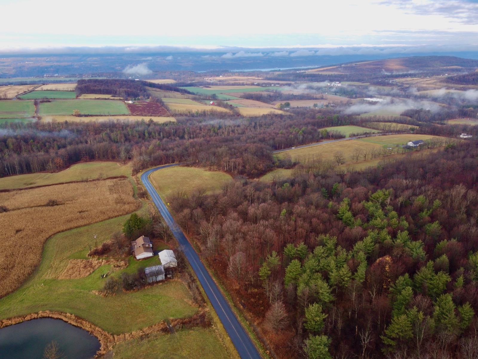 Aerial drone shot of patches of low-lying fog on a rural landscape.