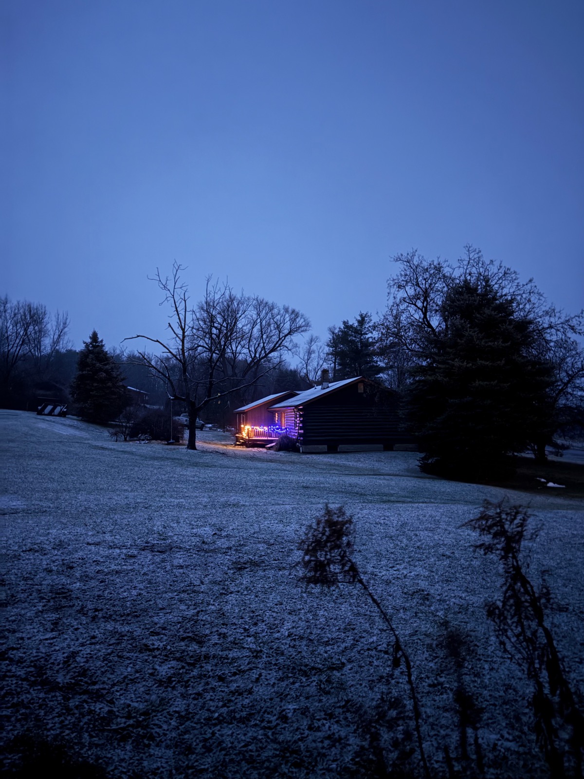 Country house in the pre-dawn twiligh with house lights shining on a snowy landscape