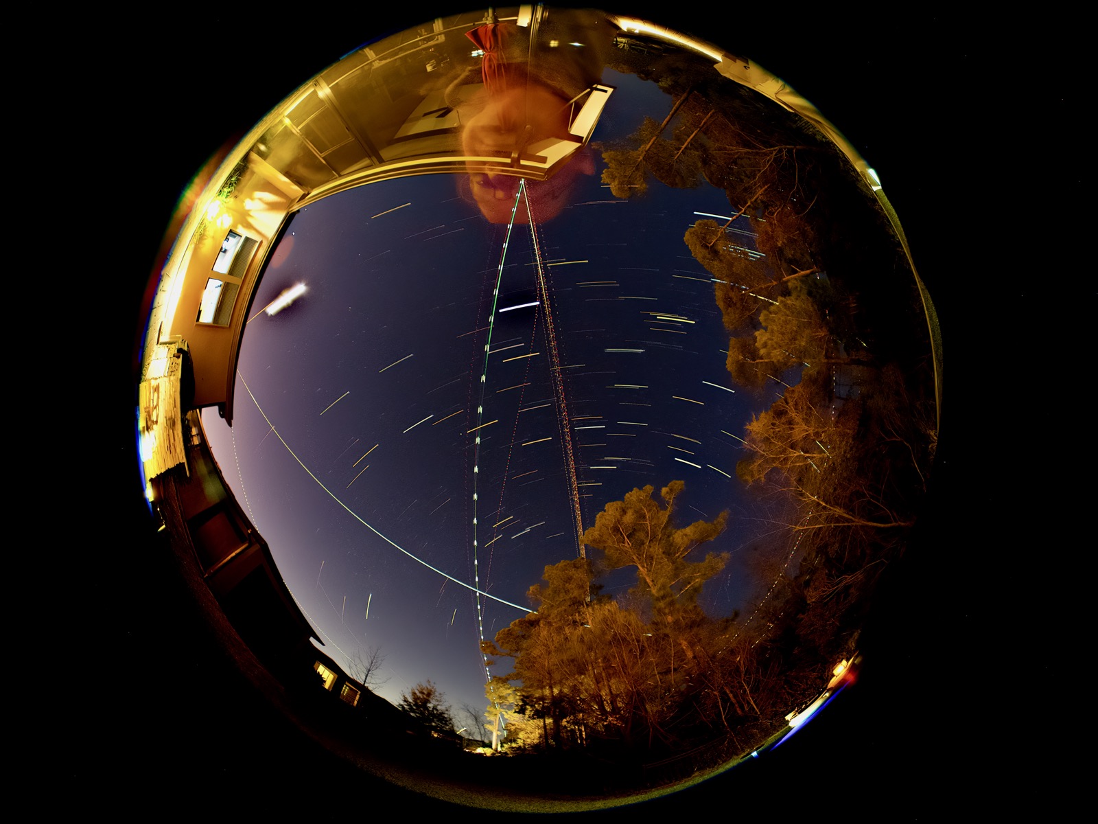 Circular fisheye image of the overhead night sky with star trails, aircraft and the International Space Station overhead.