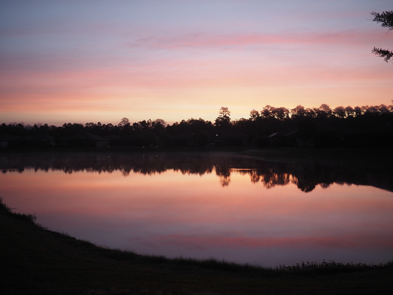 Colorful morning twilight clouds reflected in a suburban retention pond