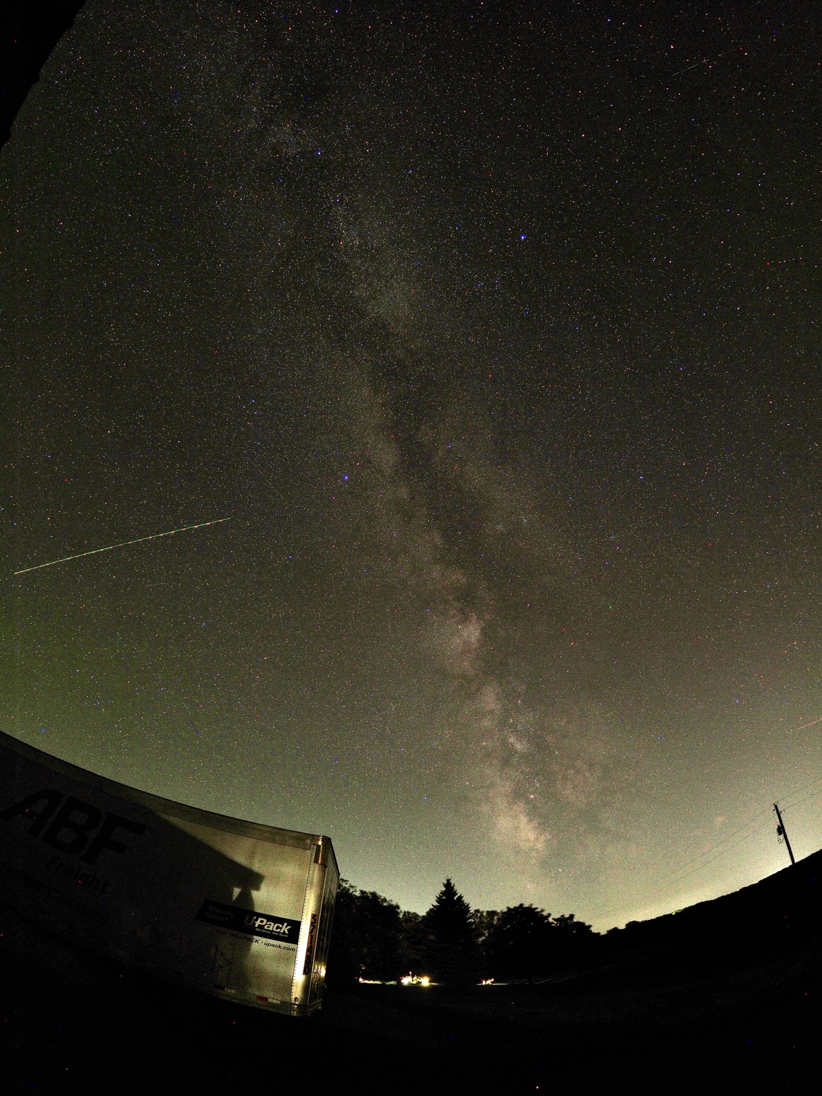 Fisheye view of the Milky Way looking southwest with a moving trailer in the lower left foreground