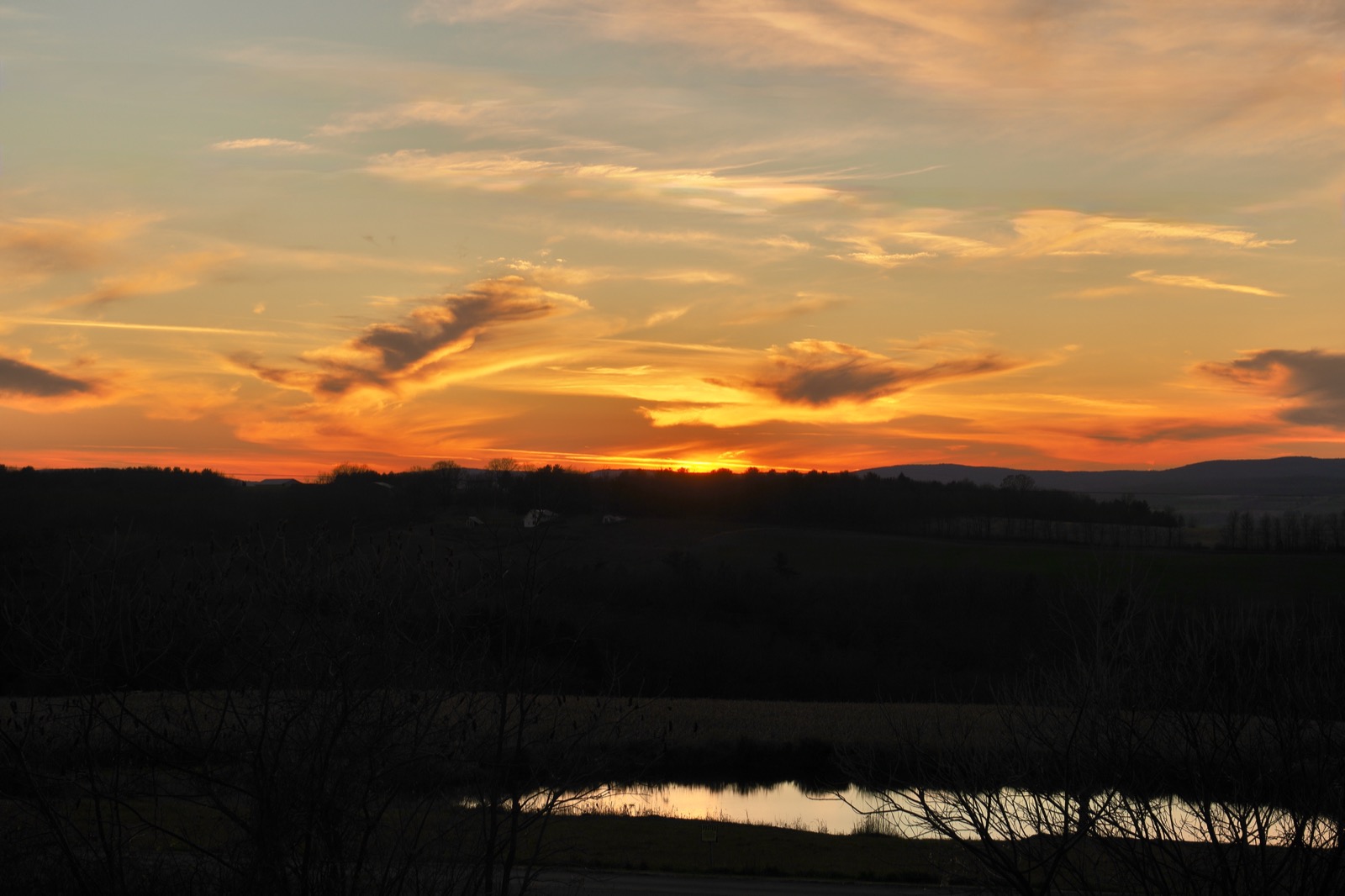 Clouds against the sky illuminated in red and gold from the sun beneath the horizon