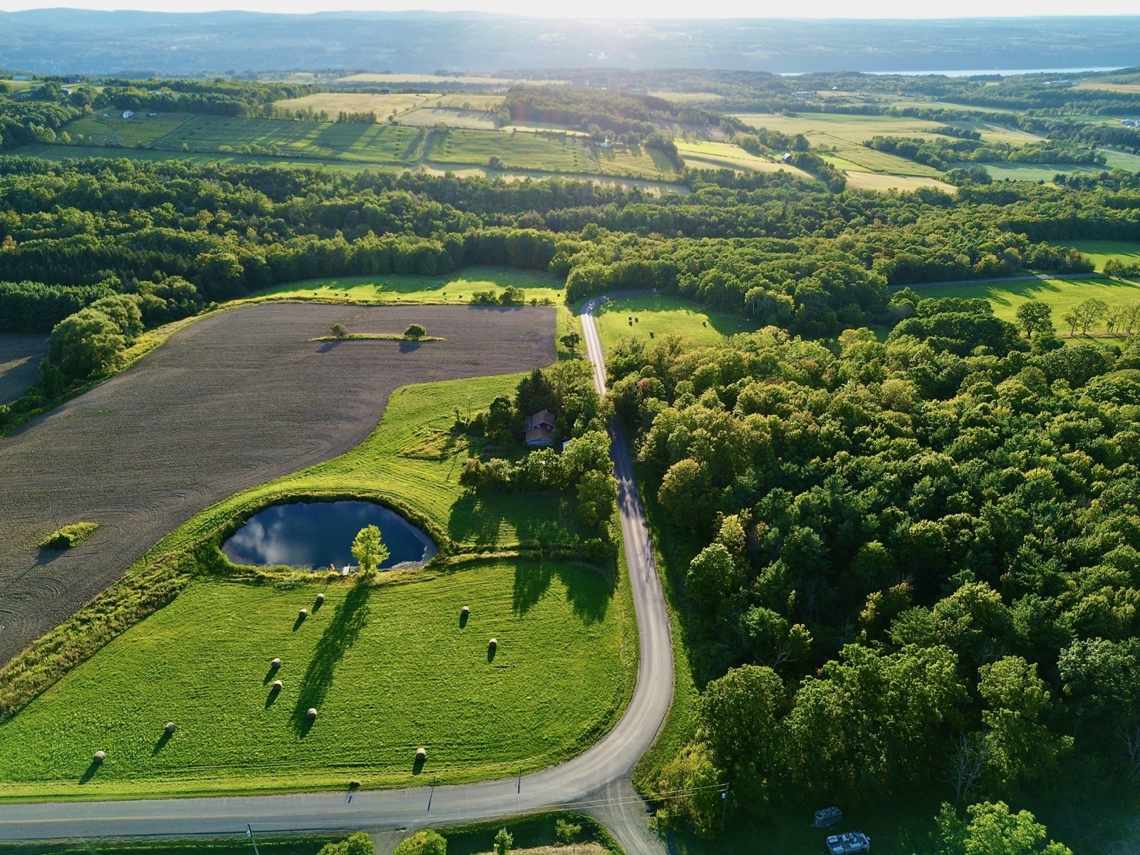 Drone shot looking west as the evening sun casts long shadows on open fields.