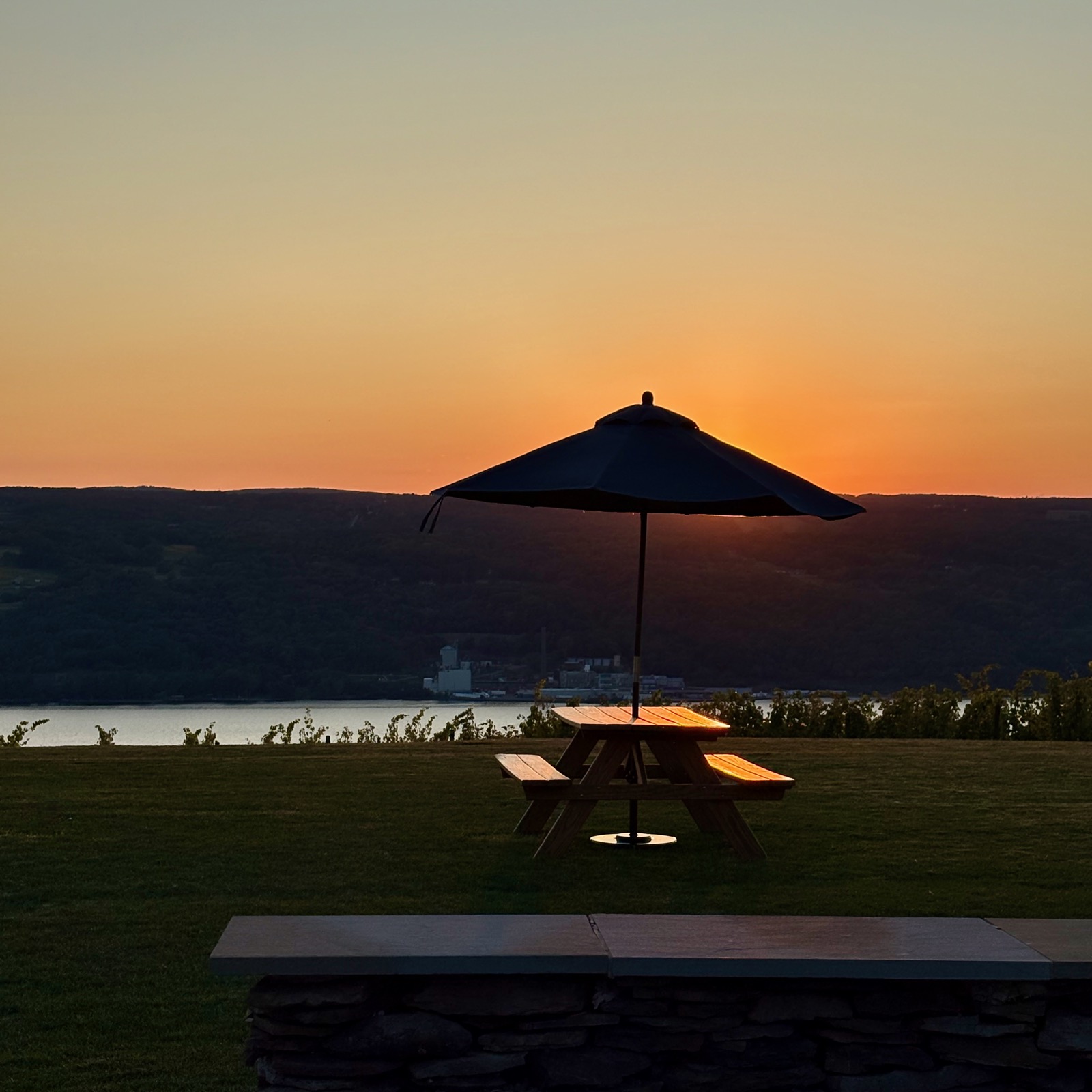 Picnic table and sun umbrella silhouetted against the setting sun