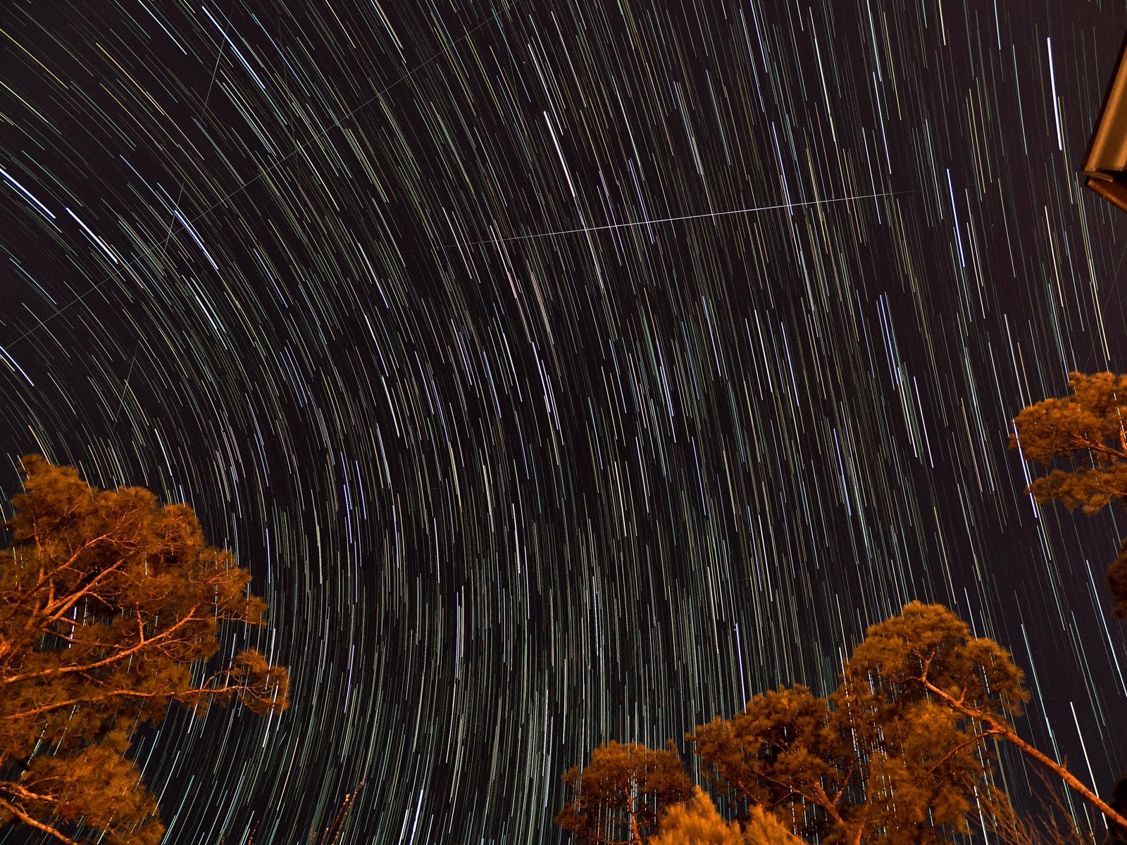 Live composite 30 minute exposure showing star trails and satellite tracks overhead before dawn.