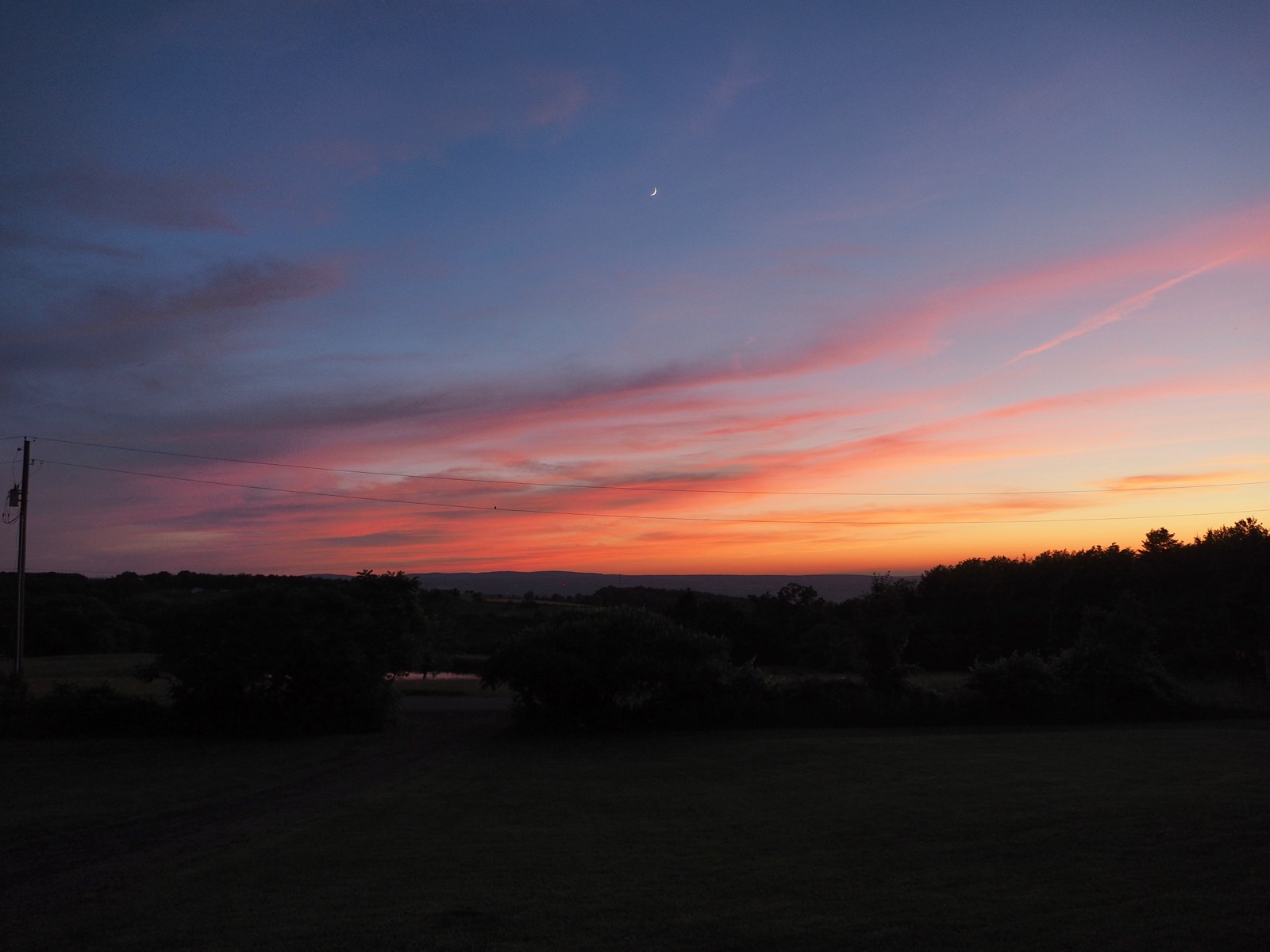 Crescent moon above wispy red clouds