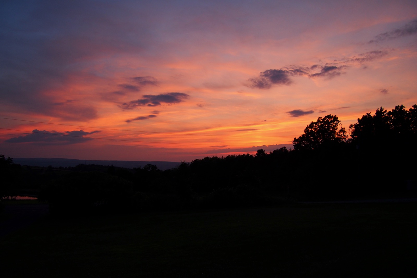 Evening cloudscape after sunset, red and gold clouds, trees silhouetted