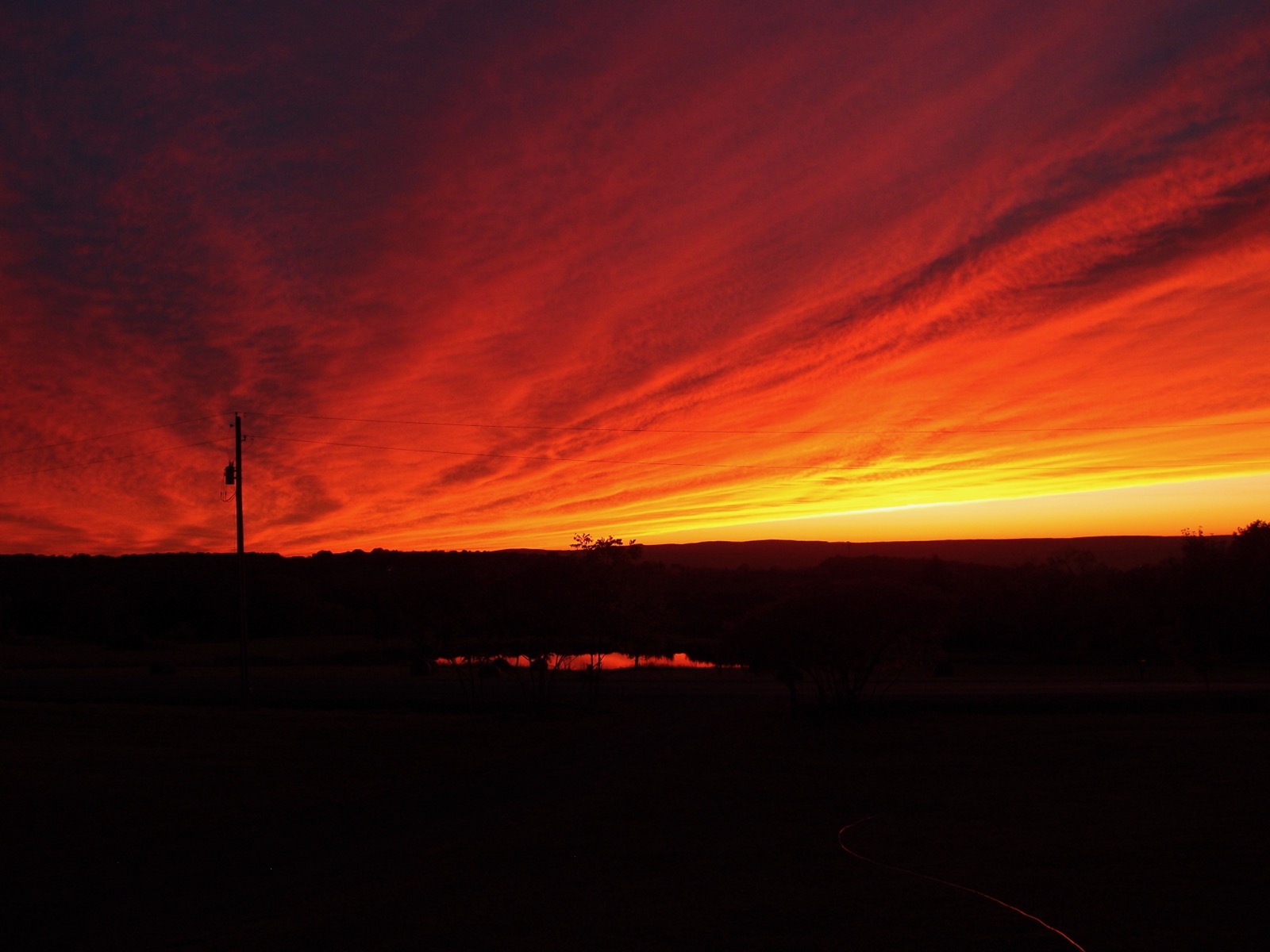Expansive cloud layer illuminated from below in red and orange by the sun from below the horizon.