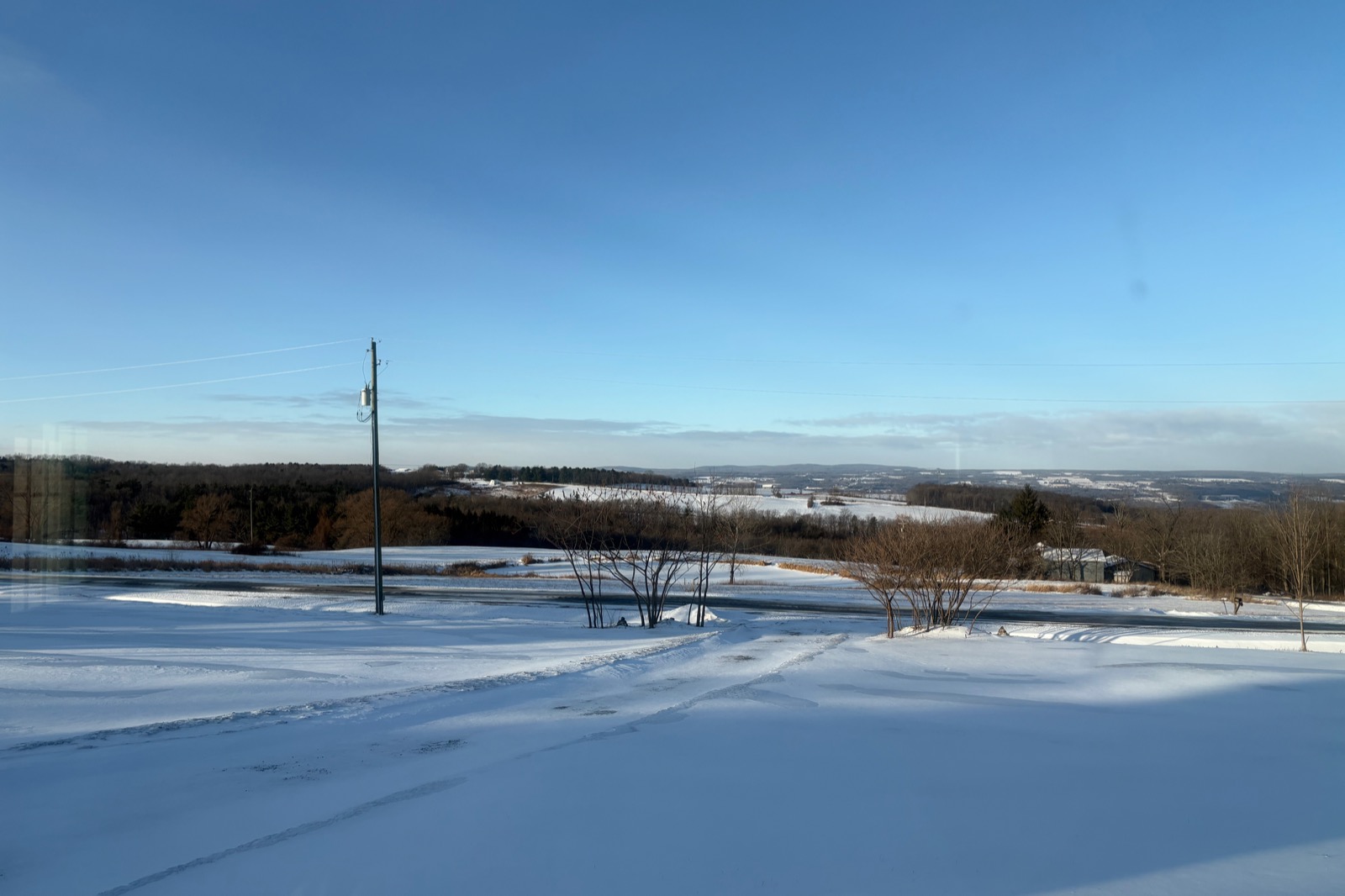 Wide angle snow-covered rural landscape with blue skies and few cloud.
