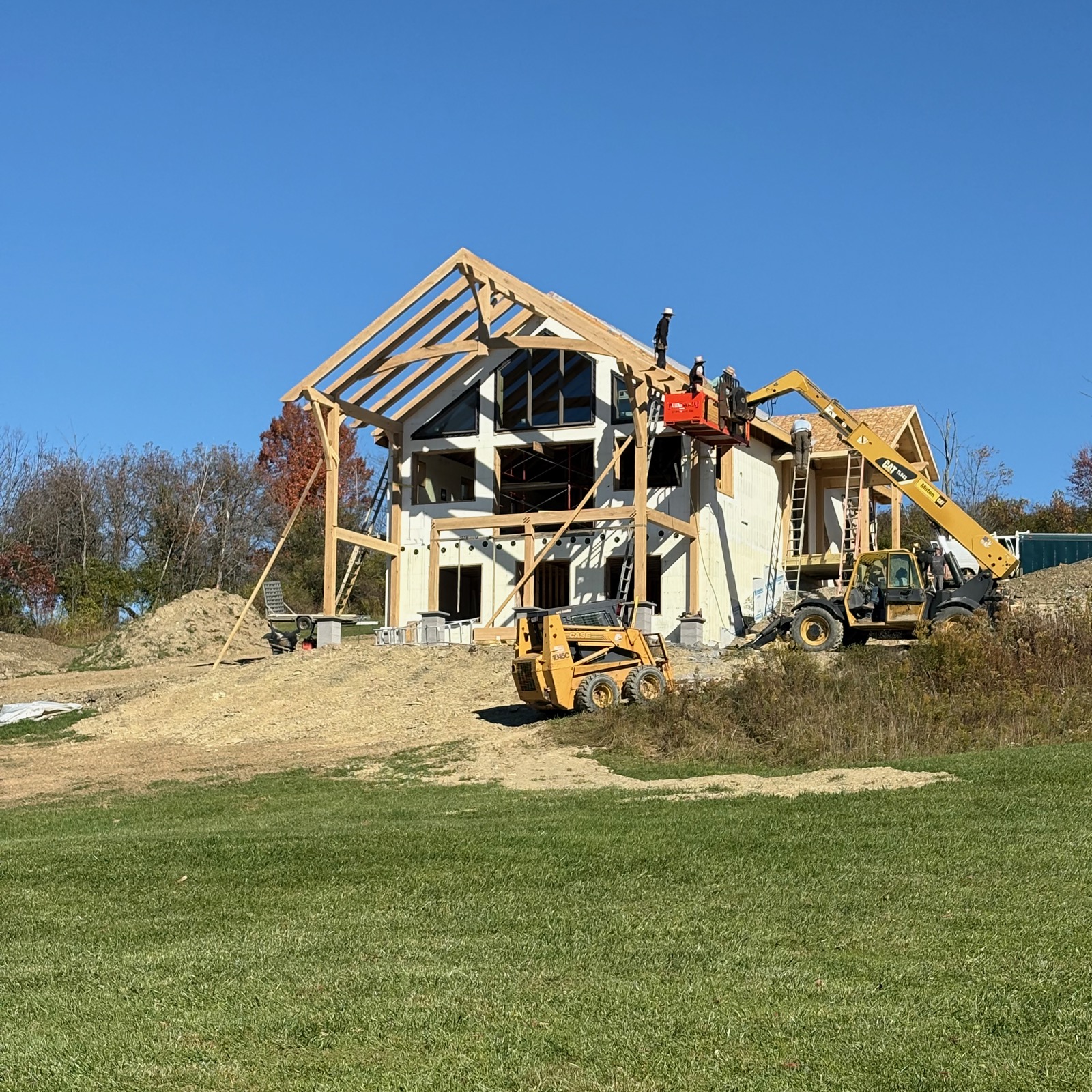 Timber frame covered deck being erected on the gable end of an ICF house.