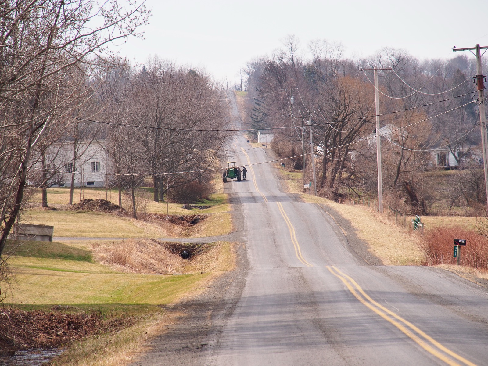 Tractor on a wavy, hilly rural road.