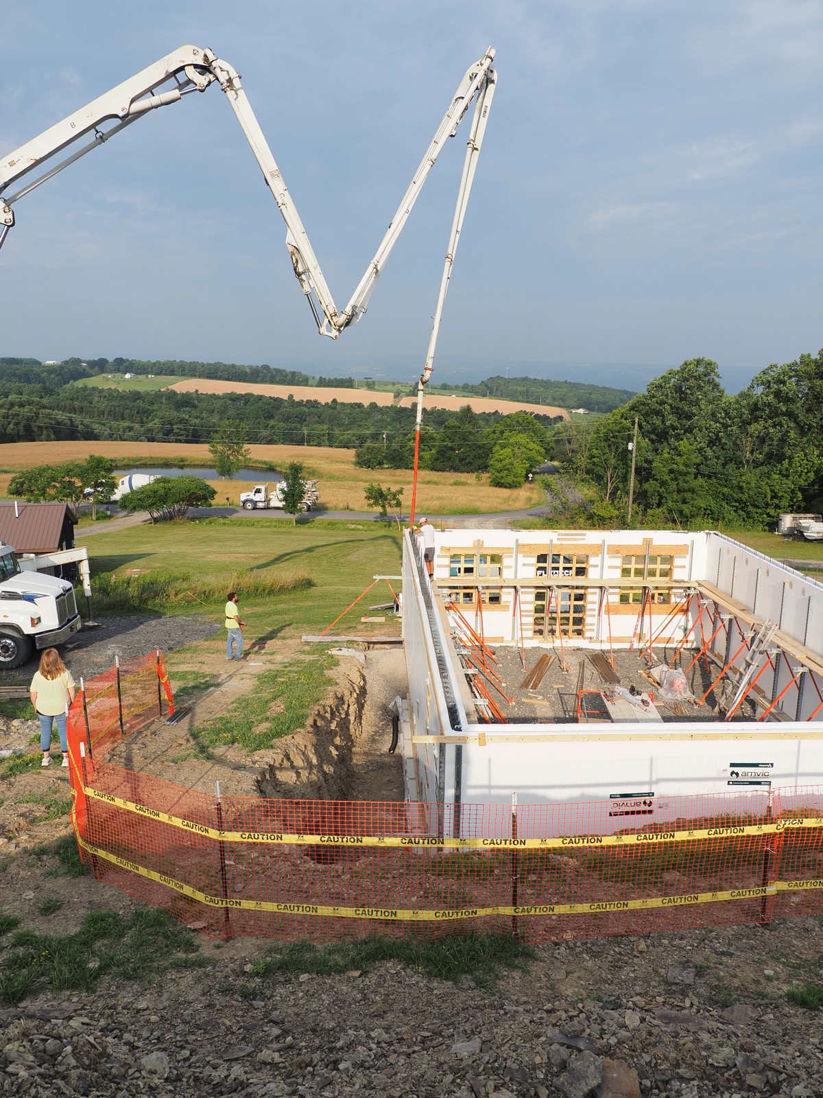 Boom from a concrete pumper truck over an ICF basement in a rural landscape