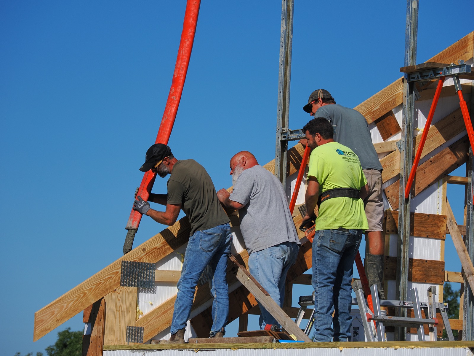 Four men on a platform pouring concrete into an ICF gable end assembly.