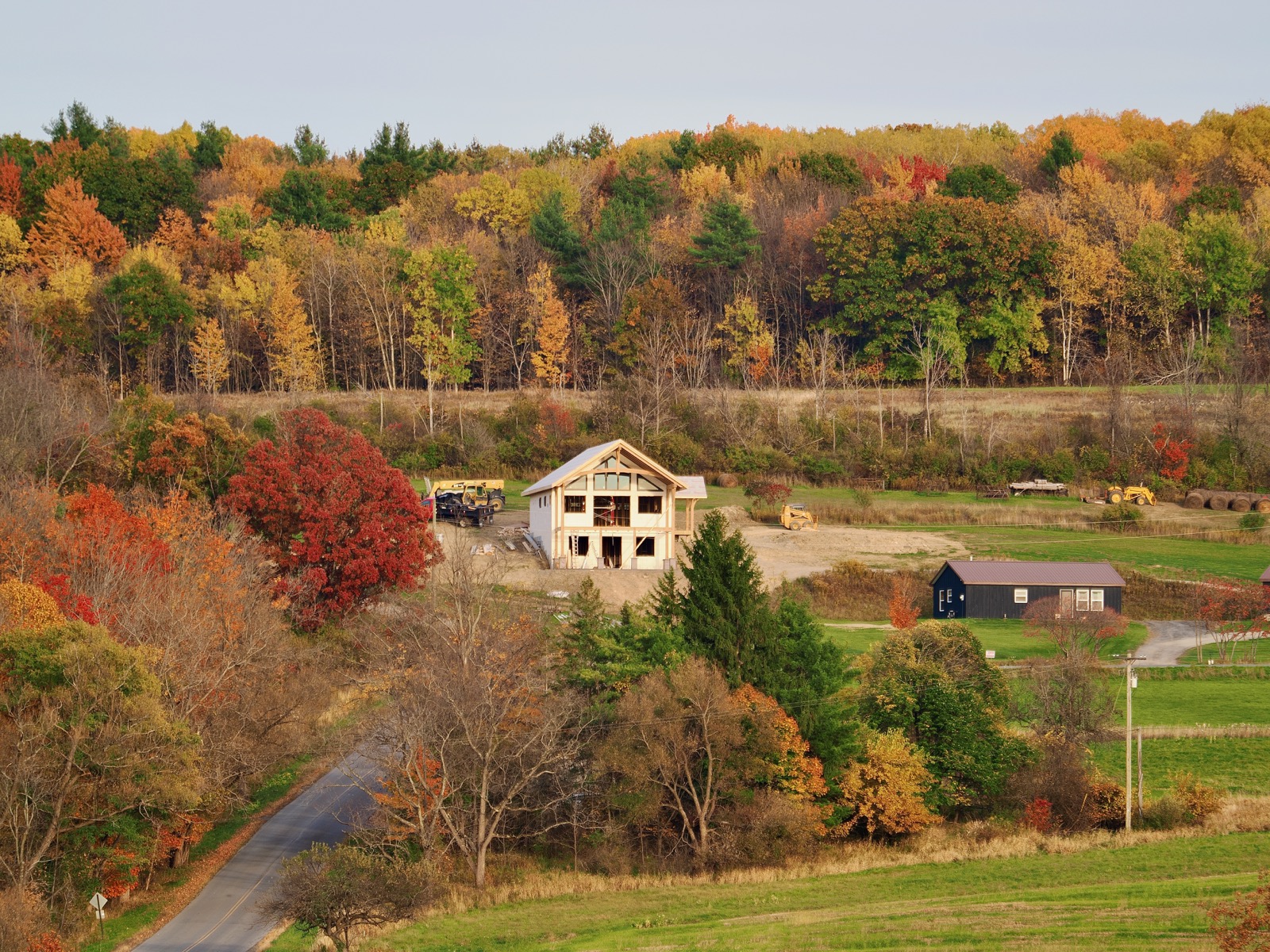 A house on a hillside with a background of trees in fall colors