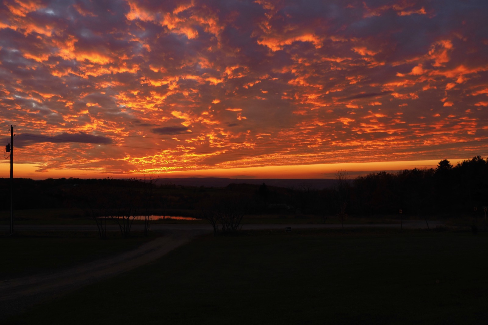 Low clouds illuminated in red and gold from below by the setting sun.